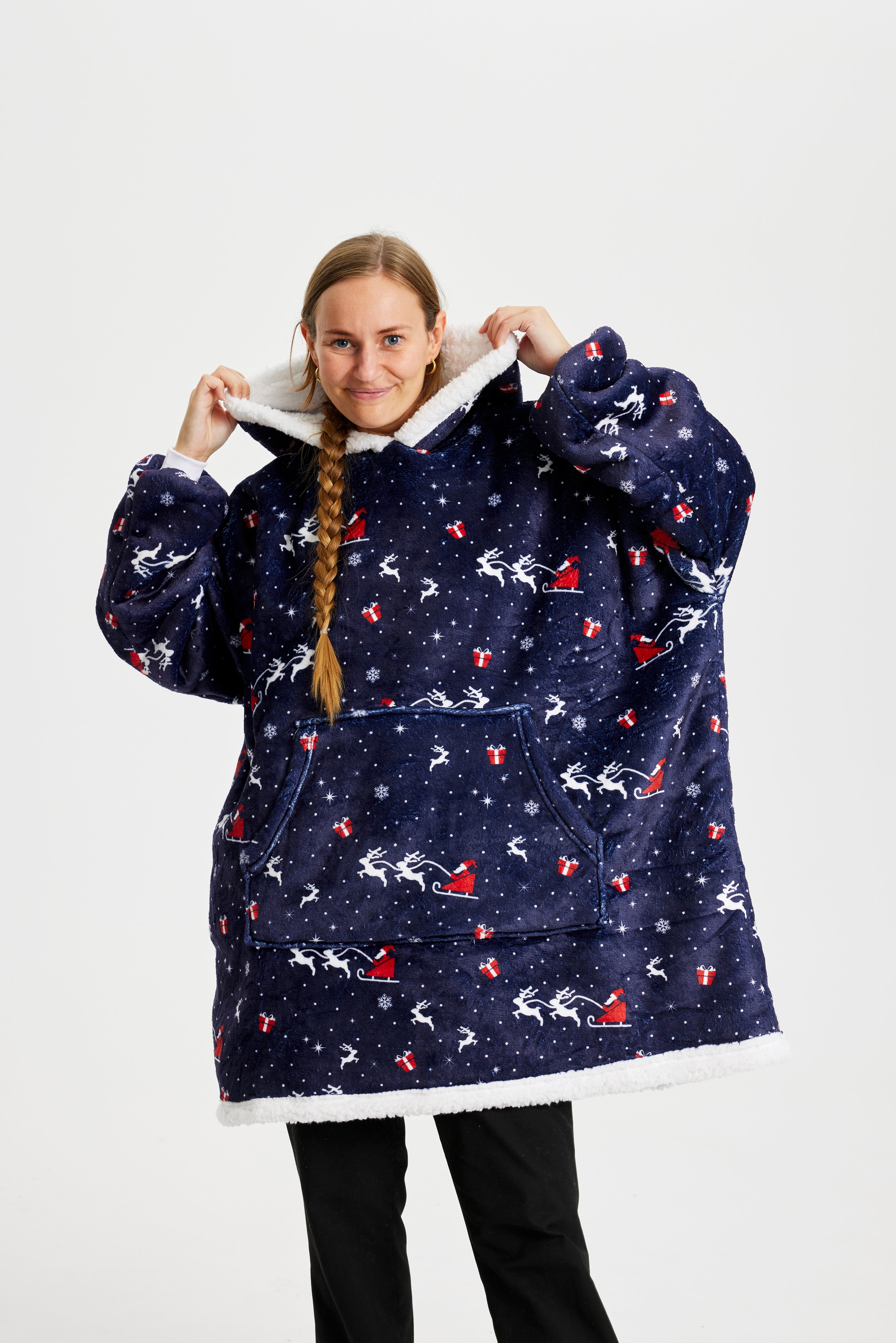 Een poserende vrouw in een blauwe kerst hoodie met kerstprint.